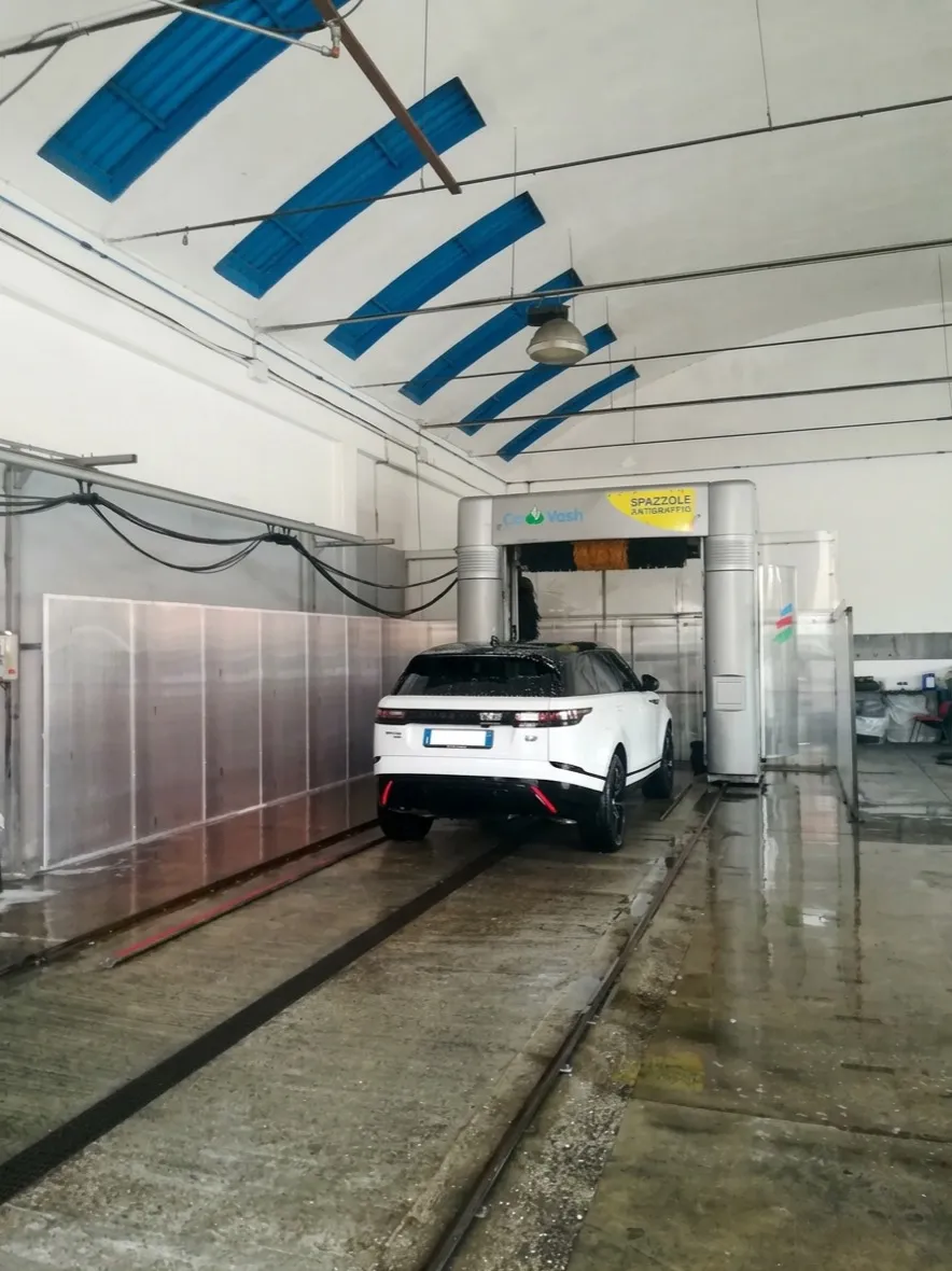 Range Rover bianca sotto il portale di lavaggio con spazzole antigraffio